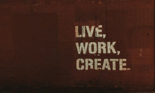 A painted wall which reads "Live, Work, Create", a central theme of the His and Her FI Post FI blog